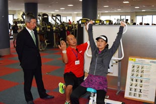 インストラクターの指導でストレッチ器具を体験する沢松プロと、それを見守るダンロップスポーツ野尻社長(写真左)